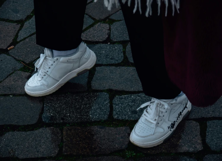 a person in white tennis shoes walking on pavement