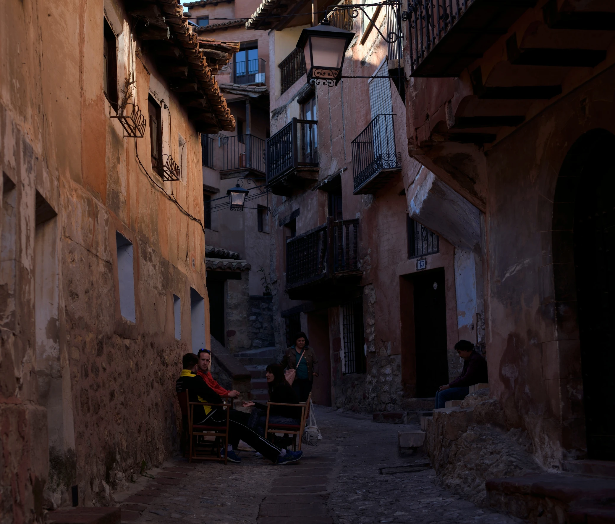 two people sitting on chairs in an alleyway