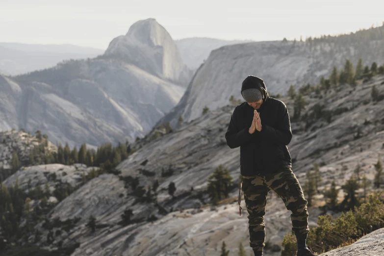 man standing on rock with his arms crossed looking at mountains