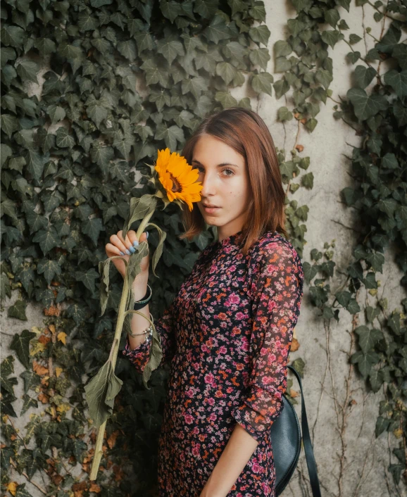 the girl has long red hair wearing a dress and is holding a sunflower