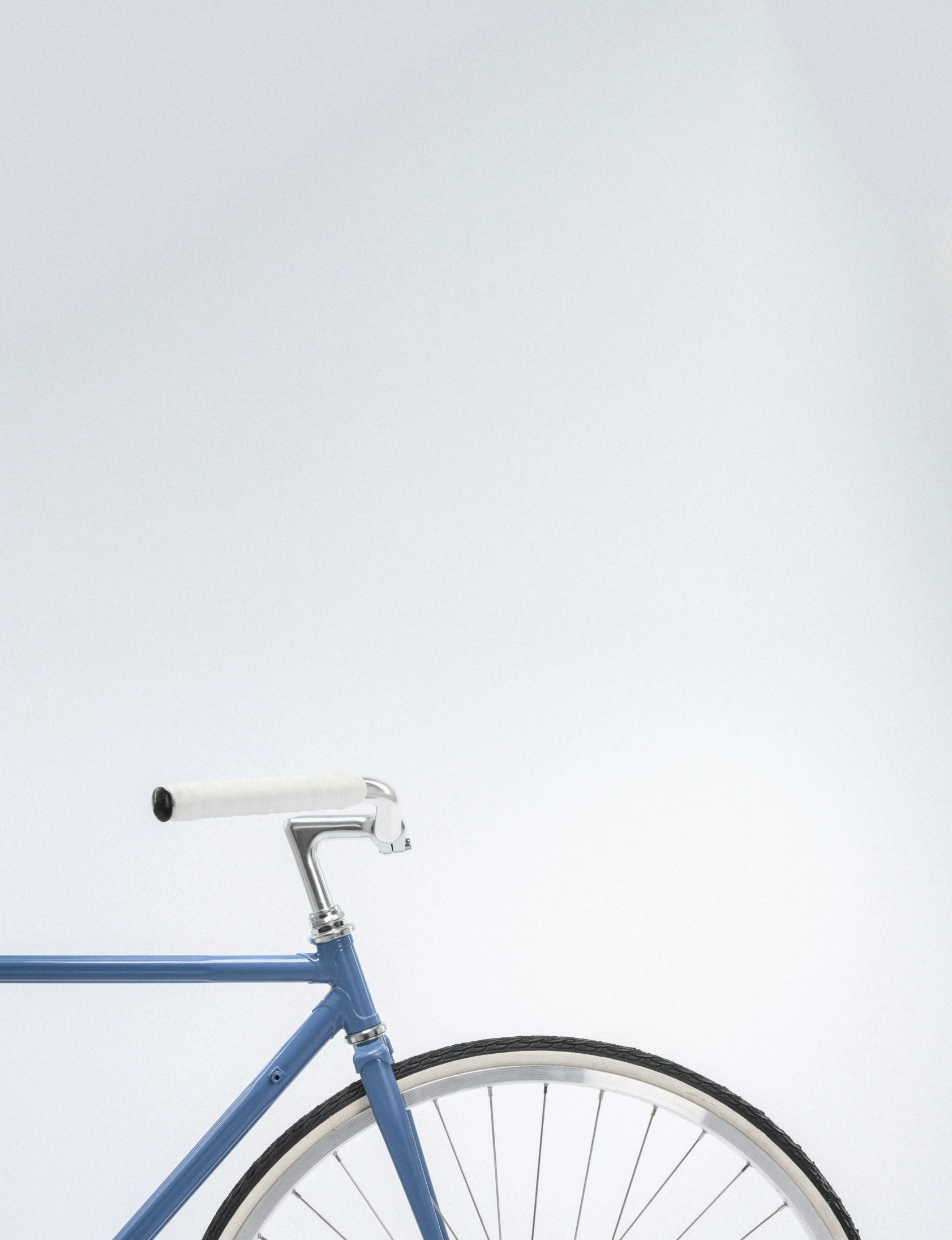 the front wheel of a blue bicycle against a white wall