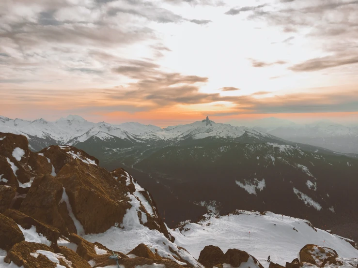 some snow mountains and some orange and white clouds