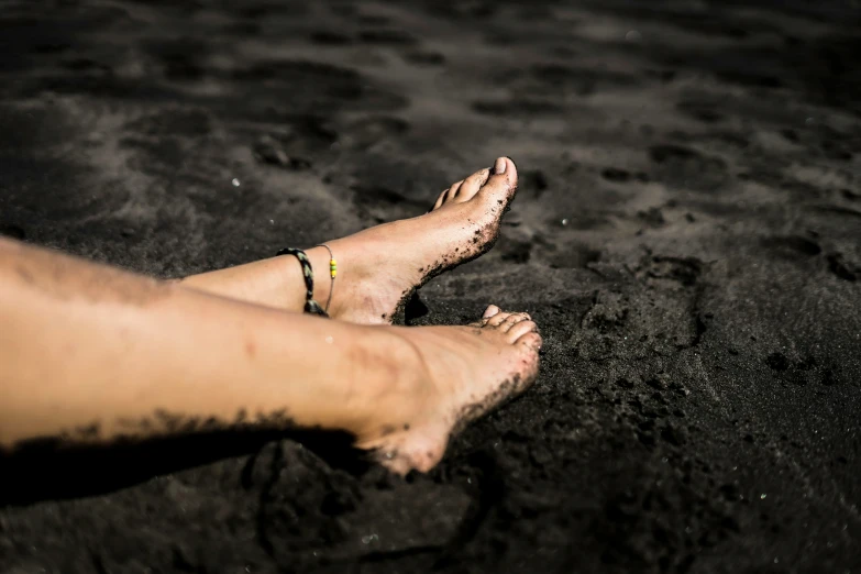 a person's bare feet and their sand are visible