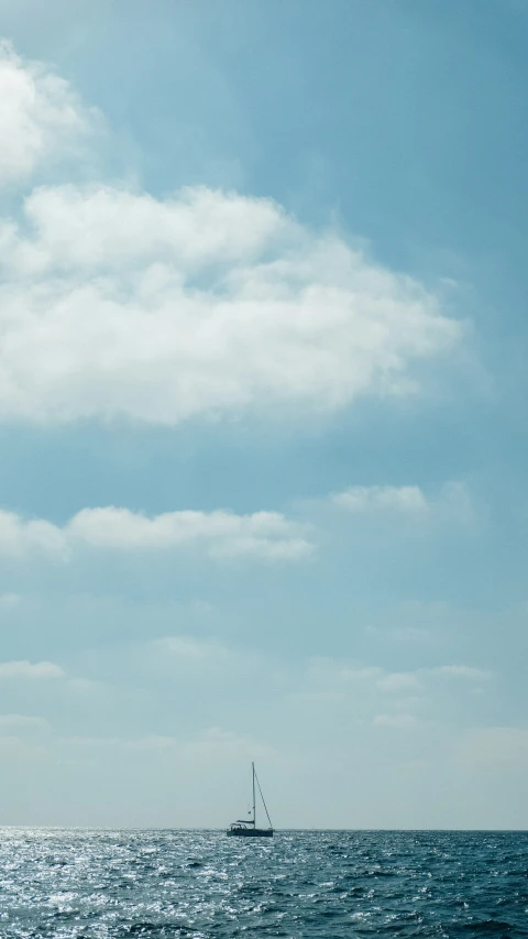 sailboat in blue ocean with white clouds in the background