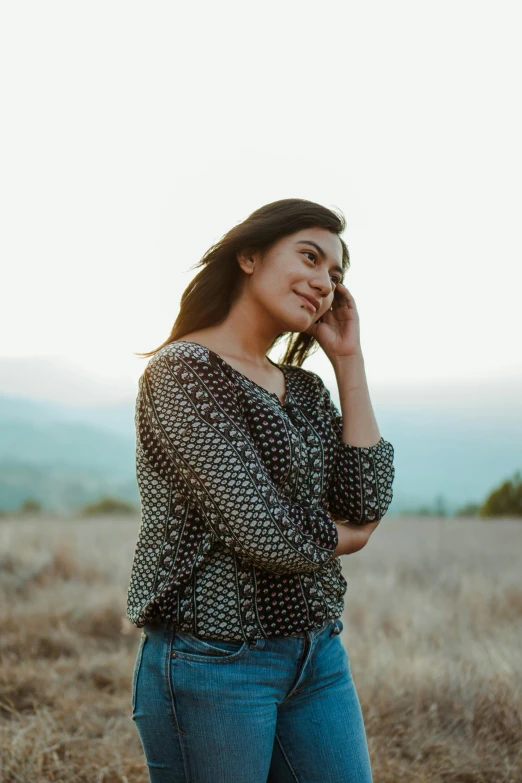 a woman is in a field, talking on the phone