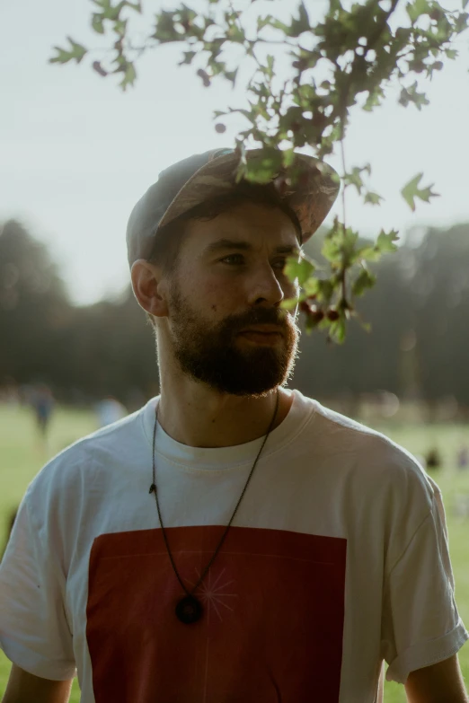 a bearded man stands outside in the sun