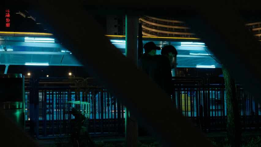 two people stand on a fence watching the night