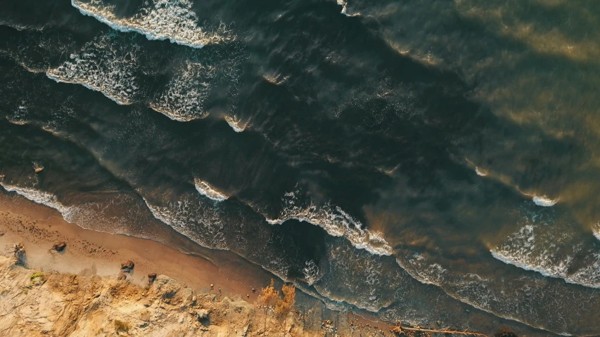 aerial view of a beach and ocean with white foam