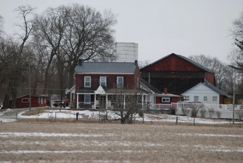 a snow covered ground near two barns and trees