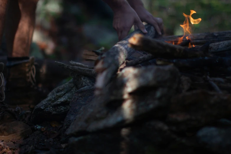 a man putting fire wood in the ground while wearing hiking gear