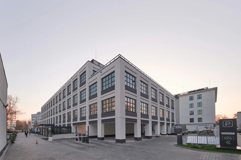 a long grey building with lots of windows next to trees