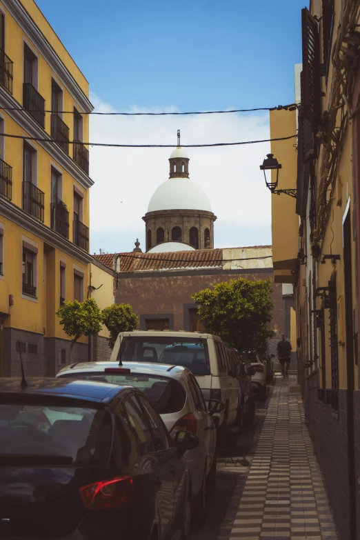 a very narrow street with lots of parked cars