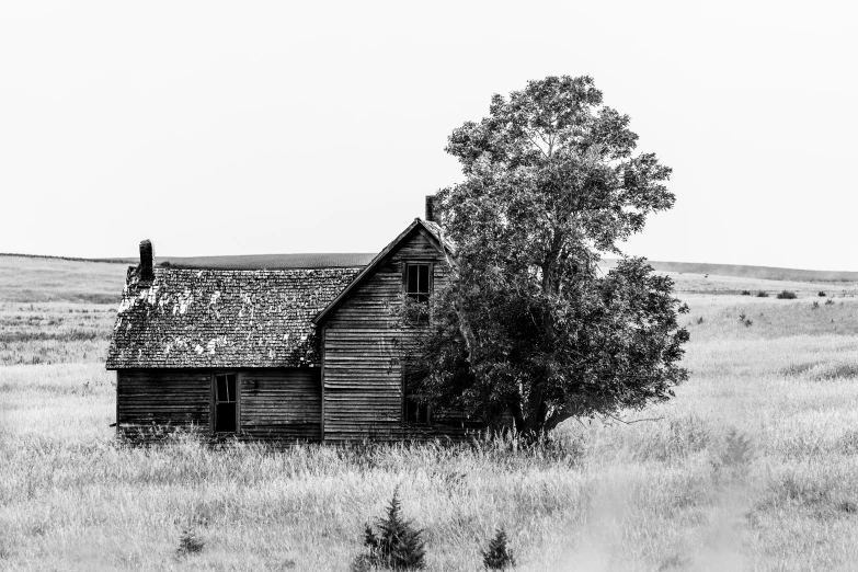 an old wooden building sitting in a grass field