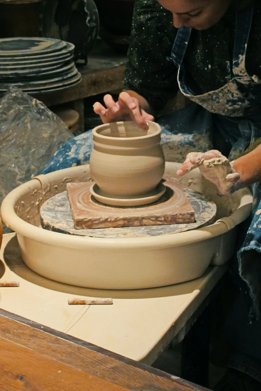 a person making a clay pot out of clay