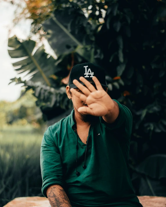 a man in green sits on a bench with his hands in the air