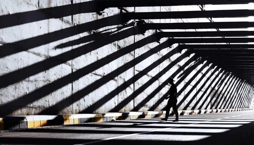 a pedestrian walking under an overpass in the dark