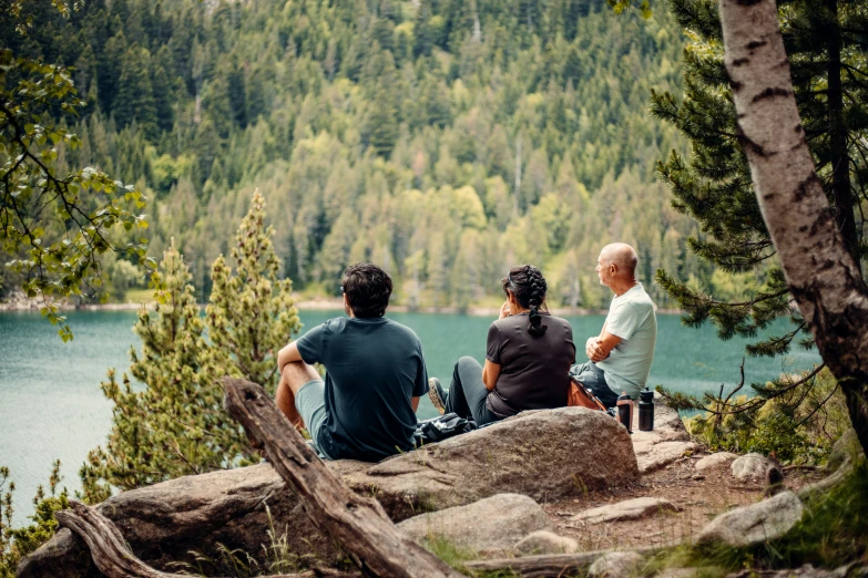 three people on top of a mountain with trees around them