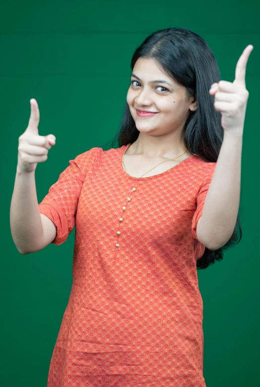 woman in an orange top pointing up with both fingers