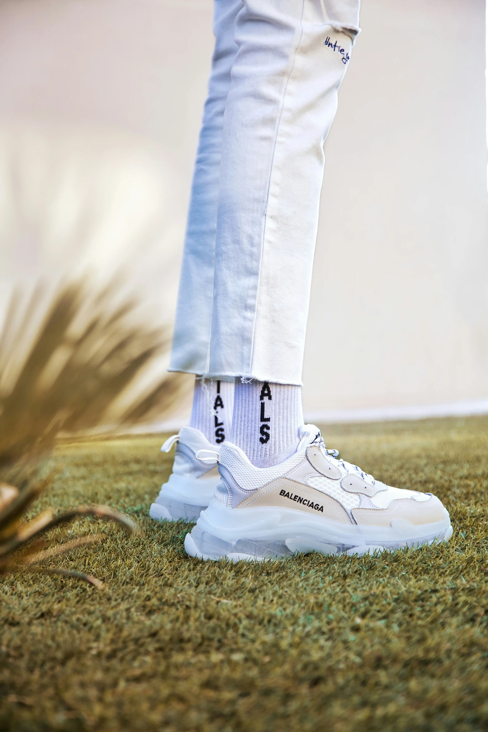 person wearing white sneakers and jeans, walking across grass