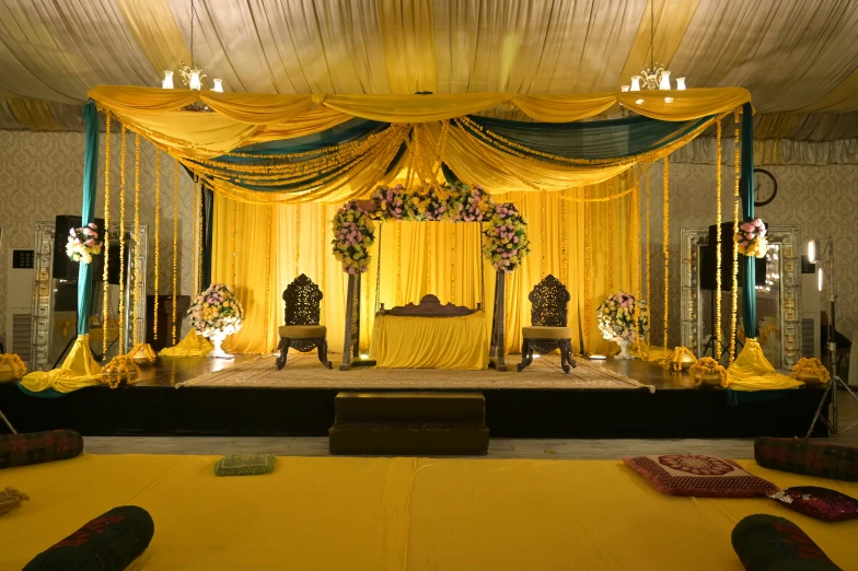 an indoor event room that has a stage decorated with yellow ds