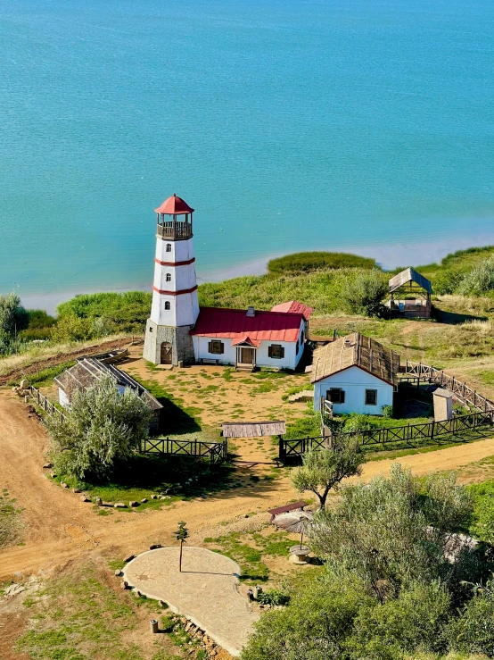 an aerial po of a lighthouse on a hill near the ocean