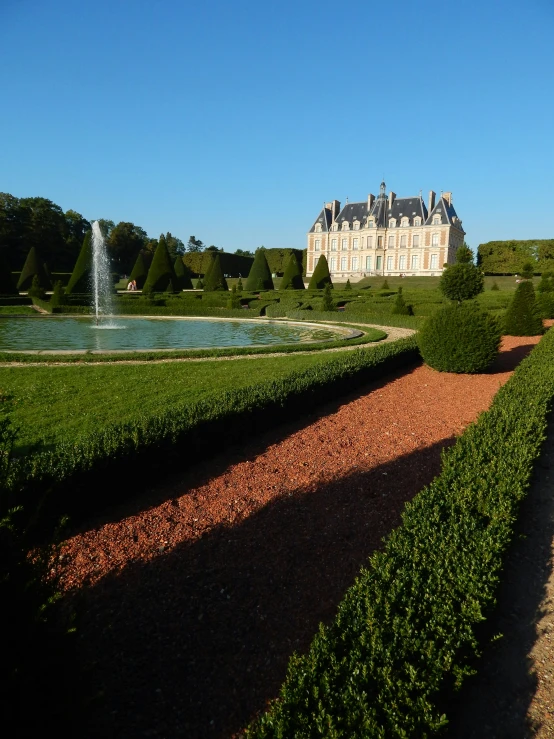 an estate with large garden and fountain in front