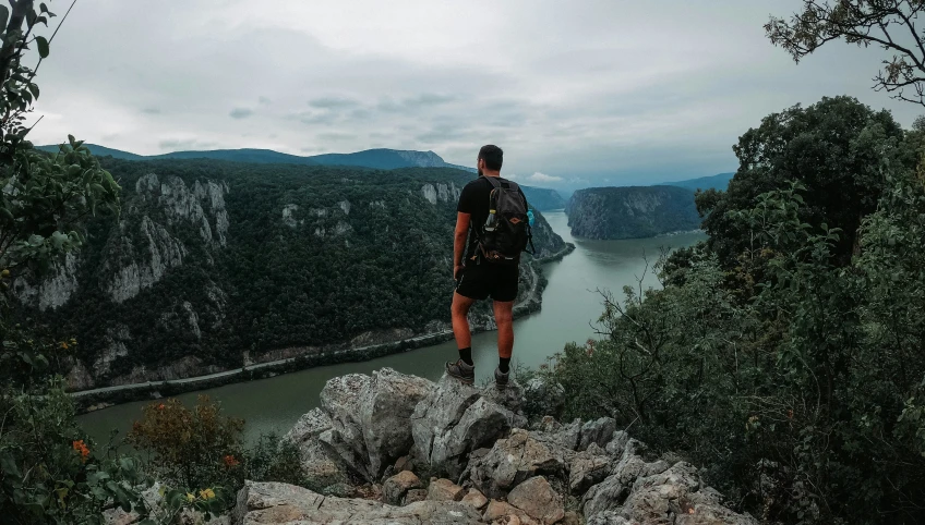 man standing on top of a hill overlooking a lake