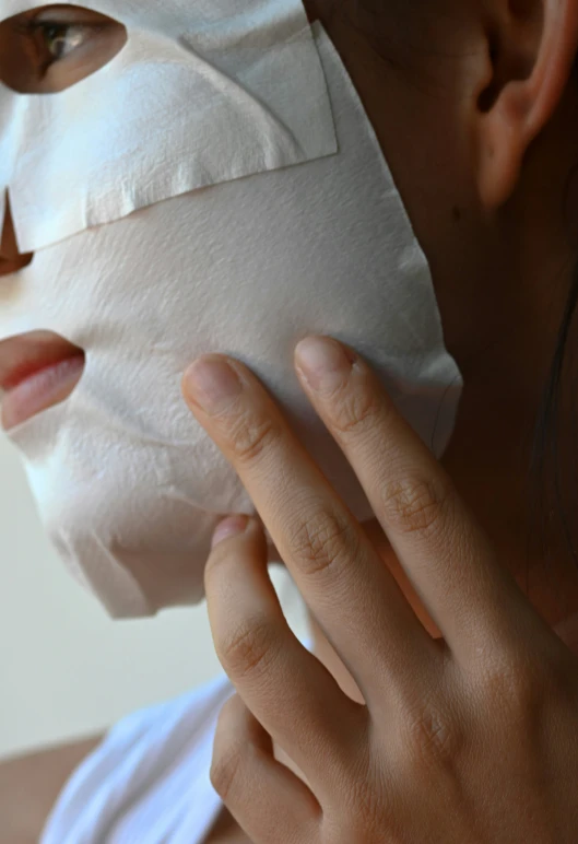 woman wearing white mask and nose piercing, posing for camera