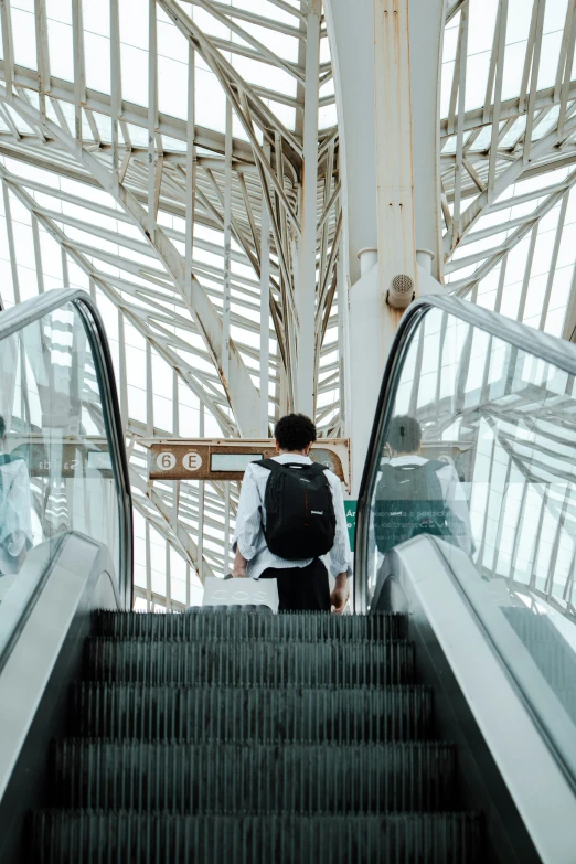 a man walking down an escalator with his backpack