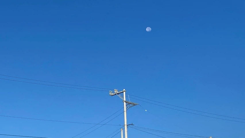 two telephone wires next to a road light and pole