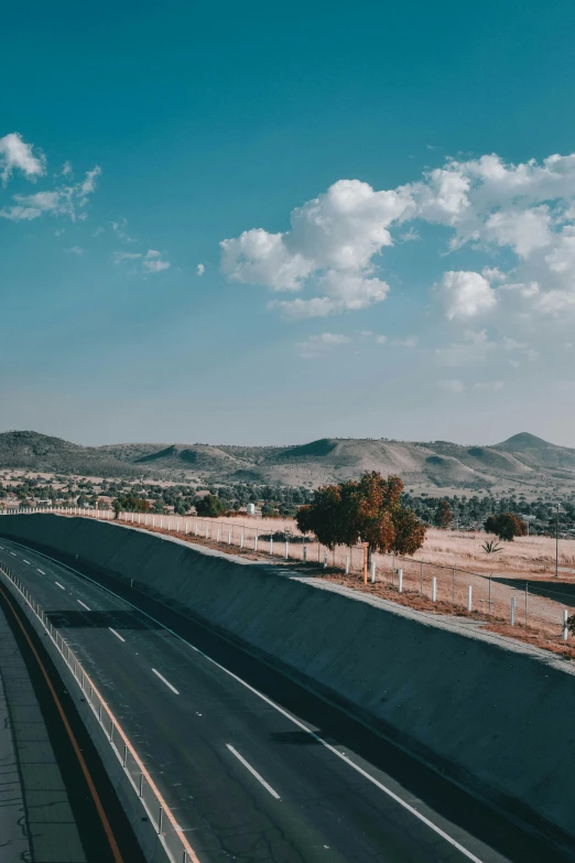 a large freeway with several lanes and lots of hills in the distance