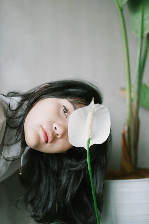 woman with long hair posing next to flower in vase