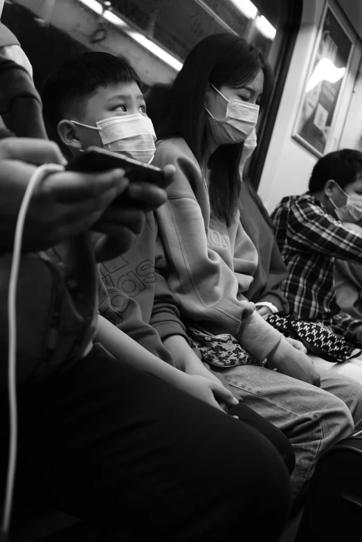 people sitting on a subway while wearing masks