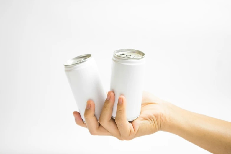 a hand holding two white cans, one empty