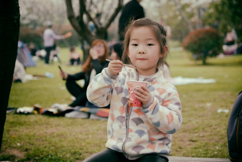 a small child holding onto a straw and sitting on a bench