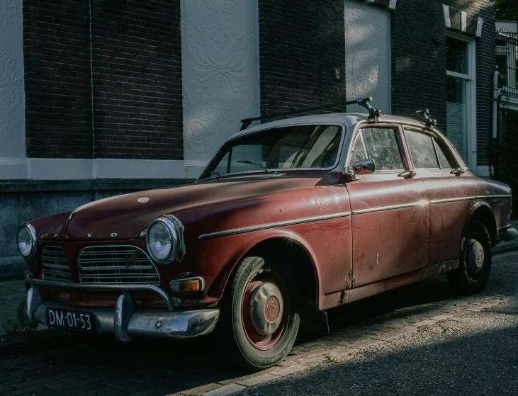 an old style, brown, car is parked on the curb