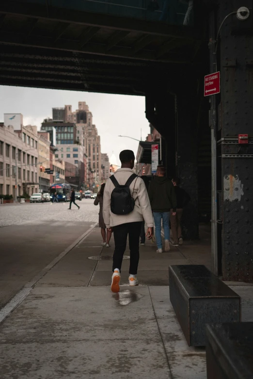 a man with a backpack walking under an overpass