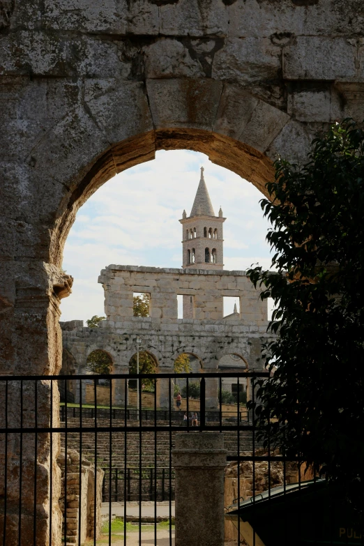 the view out a gate at a building with an arch in it