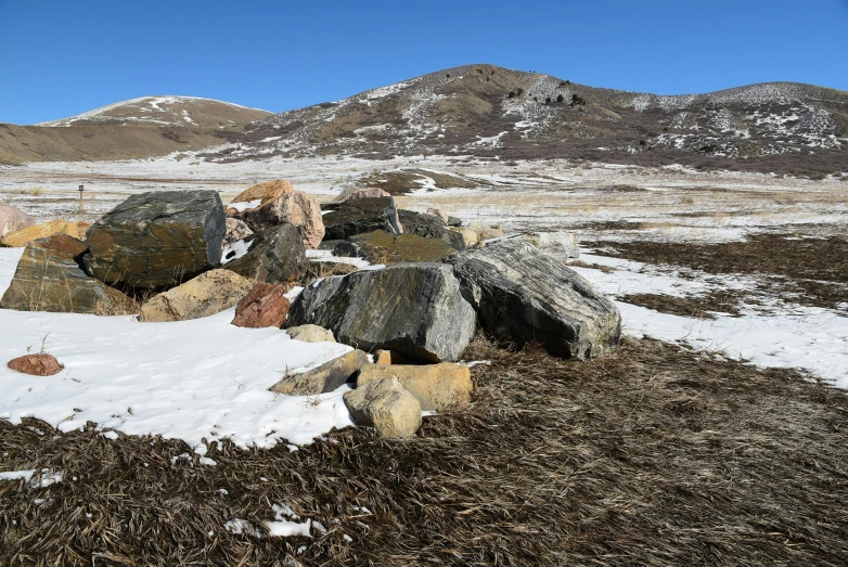 some big rocks in the snow near a mountain