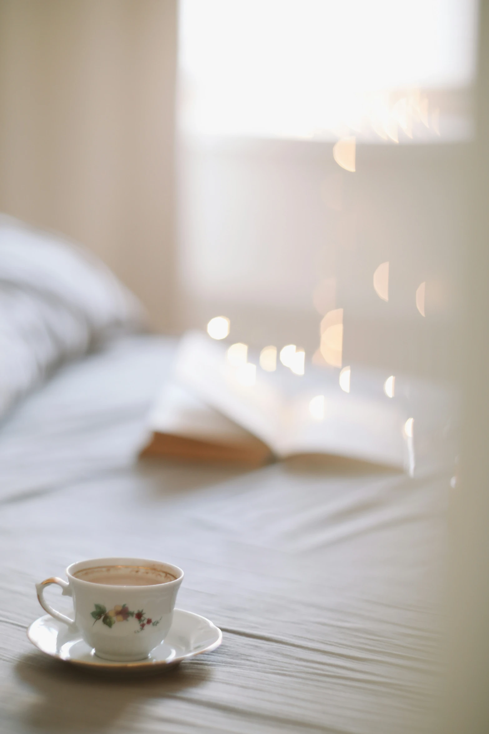 coffee cup on a bed with sunlight streaming through the window