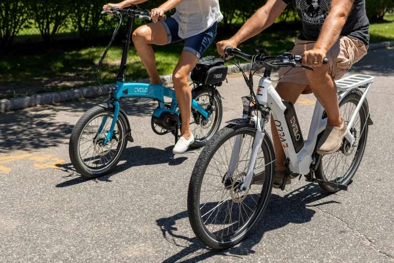 two people riding bicycles in the street with one being holding on to the handle bars