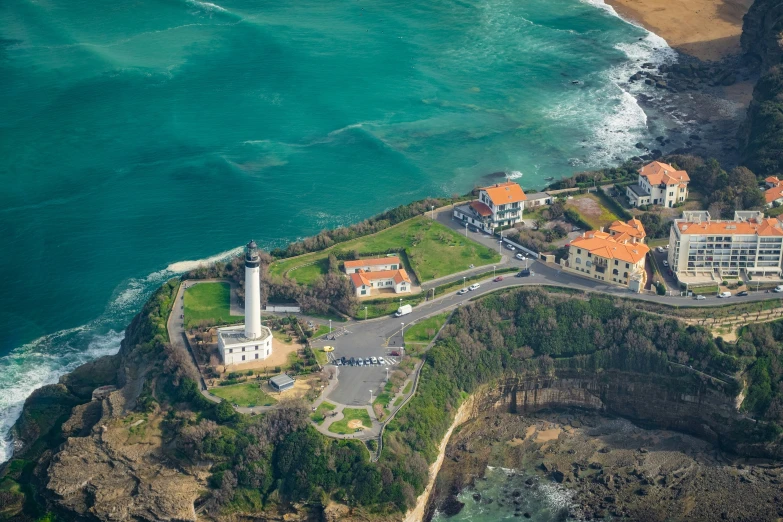 a lighthouse next to the ocean with many other buildings