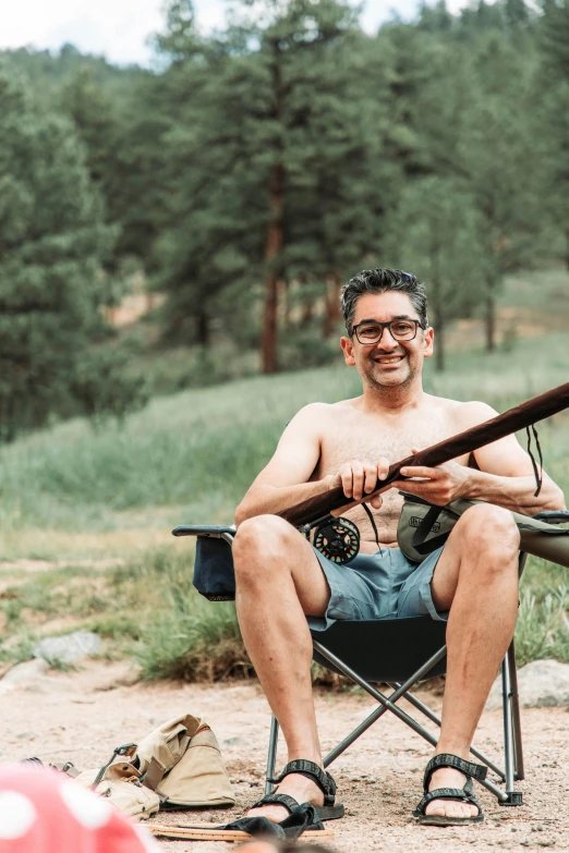 a man with a gun sitting in a camping chair