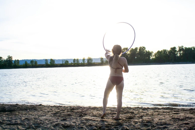 a person in a bathing suit holding up a disc on the beach