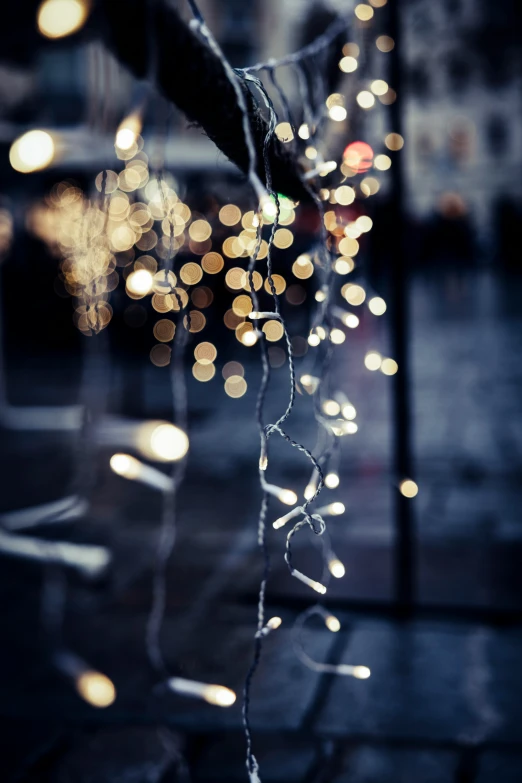 blurred lights hang from the side of a window in front of a building