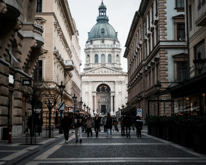 an old white building with a clock tower and many people walking through it