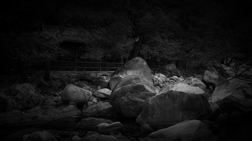 some rocks water and trees with dark skies