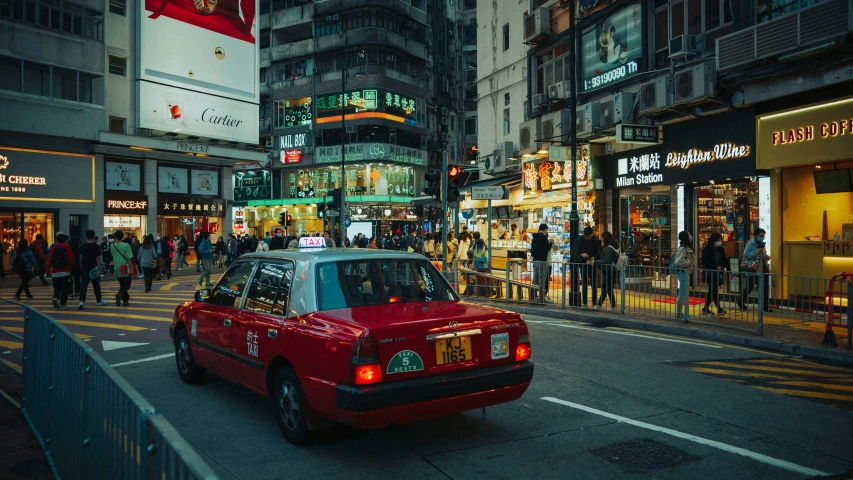 a red taxi is driving down the street near tall buildings