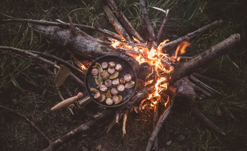 flames and pots of food cooking over an open fire