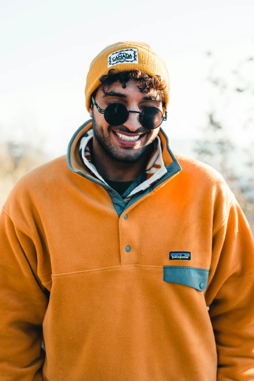 a man wearing sunglasses is wearing an orange jacket and hat